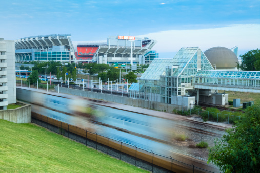 Cleveland, Ohio, USA - July 22, 2012: The Cleveland Browns Stadium with a freight train passing on the lake front tracks. Train is motion blurred. The North Coast Metro station is on the right.