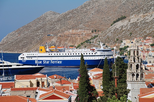 Symi, Greece - June 25, 2011: Blue Star Ferries ship Diagoras arrives at Yialos harbour on the Greek island of Symi. The 141 mtrs long ship was built in 1990.