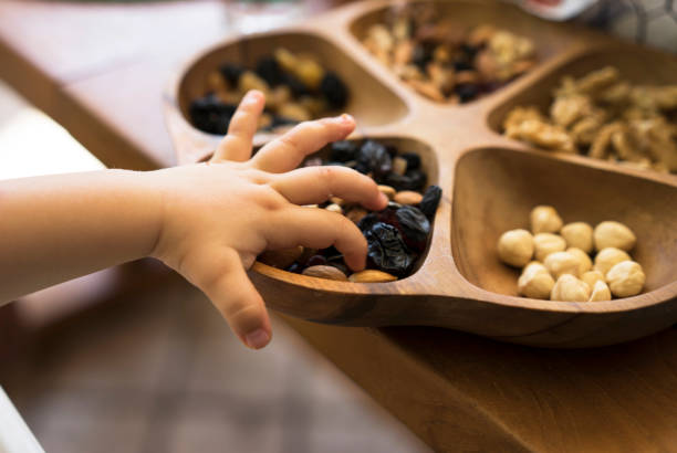 Toddler picking almonds from a bowl with mixed nuts