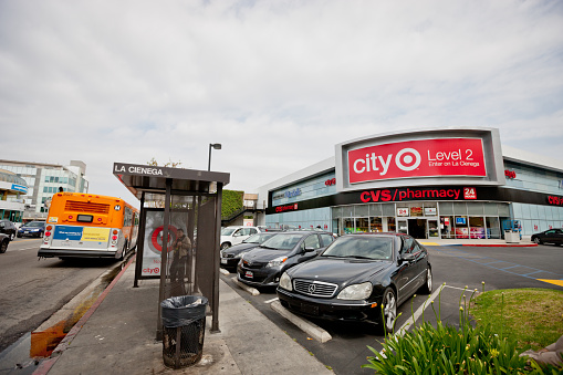 Los Angeles, USA - May 8, 2013: CVS Pharmacy located in  West Hollywood, La Cienega boulevard entrance, USA. Cars parked nearby, Bus Stop Cienega on foreground, man is waiting for bus.