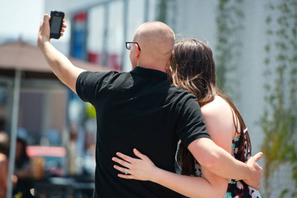 casal fazendo selfie com telefone celular na rua - smart phone iphone women mobile phone - fotografias e filmes do acervo