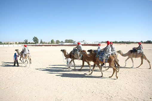 Douz, Kebili, Tunisia - September 17, 2012 : Beduins leading tourists on camels at the Sahara desert on September 17, 2012 in Douz, Kebili, Tunisia