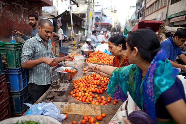 New Delhi, India - May 12, 2013.  Indian women buying tomatoes from a streetside vendor at a vegetable market in the old part of the city.