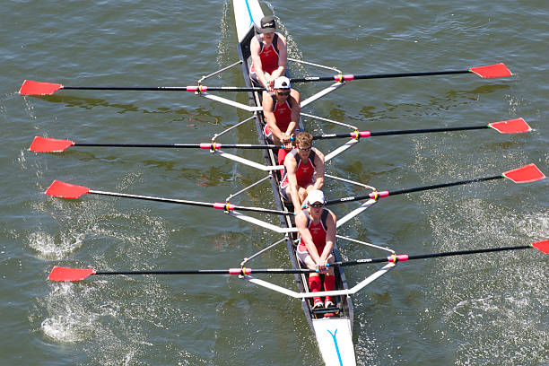 Whimsical image of a family boating on the lawn. The dad is about to wipe out on his skis. The rest of the group has a surprised look on their faces. Two of the children are rowing the boat. There is motion blur with the skier as he is falling.