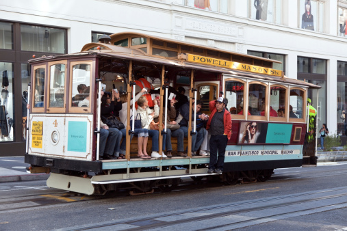 San Francisco, California, United States,- September 07, 2011: Seated tourists on the Powell-Mason Street cable car in San Francisco wave their tickets at the brakeman.
