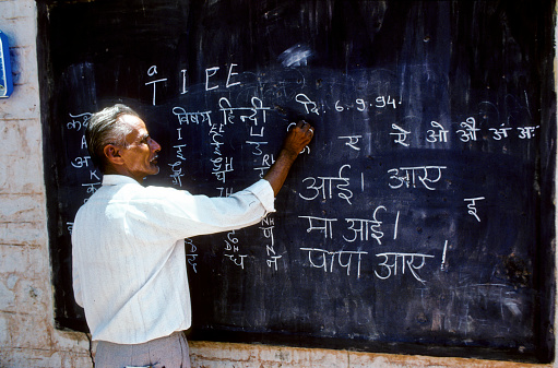 Agra, India - August 6, 1994: male teacher in India is writing on the blackboard
