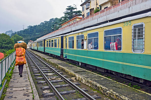 Shimla, Himachal Pradesh, India - July 28th, 2011: Man with cabbage passing by old diesel passenger train, people waiting on the train before driving on mountain railway from Shimla to Kalka in Indian Himalaya.