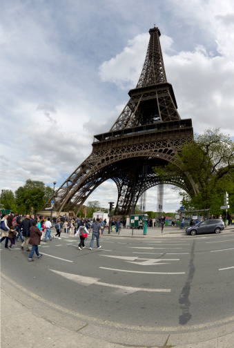 Paris, France - May 9, 2013: People crossing the street Quai Branly approaching the Eiffel Tower - the most famous Parisian Landmark - built in 1889 for the Exposition Universelle. The park Champ de Mars is seen in the background.