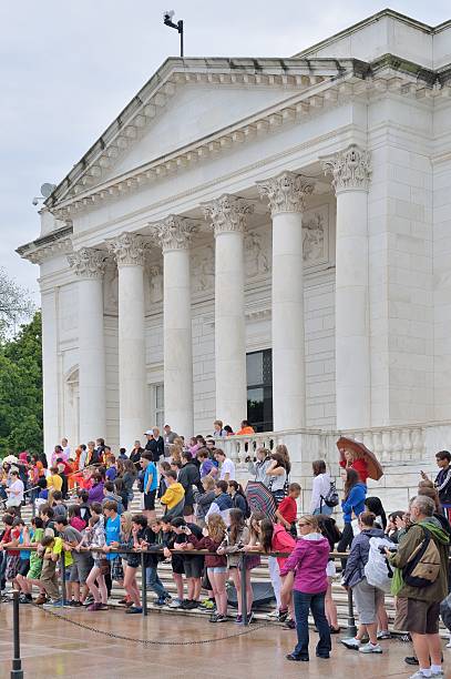 Class Trip At Tomb of the Unknowns Arlington, United States - May 11, 2013: Students on a high school class trip to Washington DC gather in front of the Memorial Amphitheater at the Tomb of the Unknowns at Arlington National Cemetery in the rain to observe the changing of the guard at the site memorial amphitheater stock pictures, royalty-free photos & images