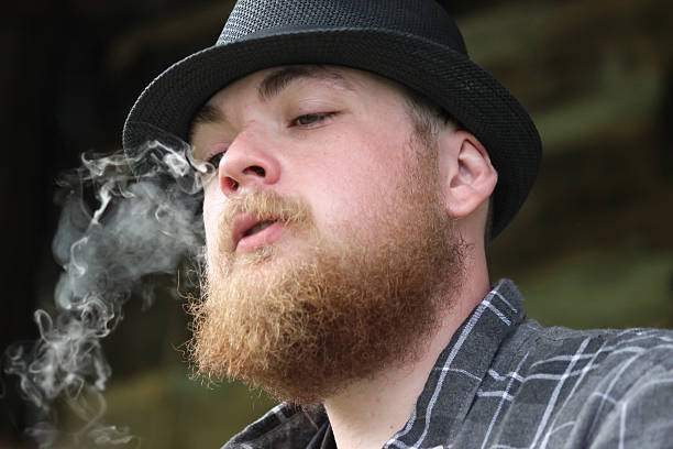 istock Bearded Man Wearing Fedora Hat Blows Smoke From Mouth 471521204