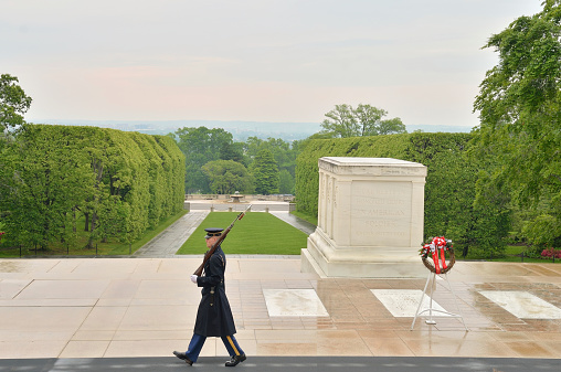 Arlington, United States - May 11, 2013: A single soldier of the ArmyÕs 3rd Infantry Regiment serves as Sentinel at the Tomb, at the Tomb of the Unknowns at Arlington National Cemetery near Washington DC. He is walking the mat in the rain with no insignia of rank carrying his handcrafted rifle.
