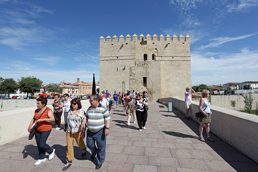 Cordoba, Spain - May 10, 2013: Tourists on the ancient bridge with tower - Torre de la Calahorra in background. Cordoba, Andalusia Spain