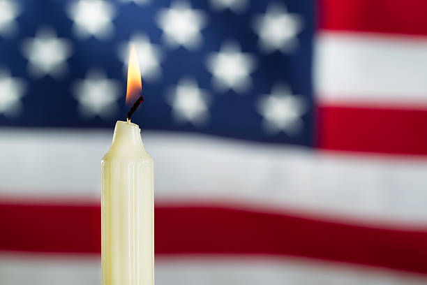 istock Lit candle with blurred out USA flag in background 471526360