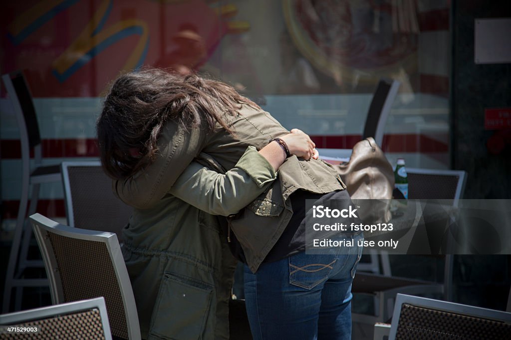 Relationships:  Two females embracing in an outdoor restaurant. Santa Monica, California, USA - May 15, 2013: Two females embracing in an outdoor restaurant.   Location is the 3rd Street Promenade in Santa Monica. 30-39 Years Stock Photo