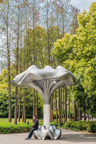 Shanghai, China - April 7, 2013: one man sitting comptemporary design public bench  in people's park  at the city of Shanghai in China on april 7th, 2013