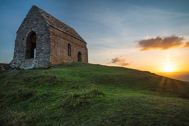 istock Romantic sunset on Cornish coast with lonelly chapel on cliff. 471529694