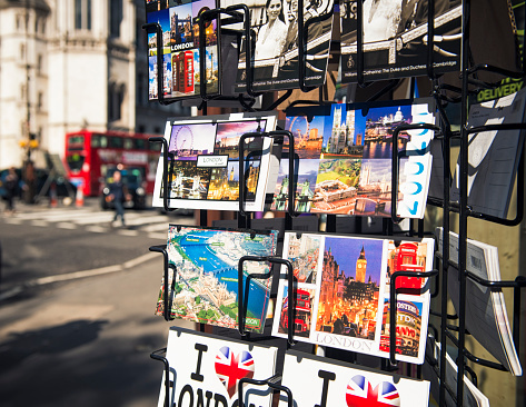 London, UK - April 30, 2012: A selection of postcards on display outside a shop in central London, with people and traffic on the street in the background.