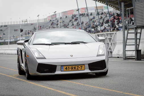 Assen, The Netherlands - May 19, 2013: Silver Lamborghini Gallardo sports car driving into the pit lane on the race track during the 2013 Viva Italia event at the Assen TT circuit.