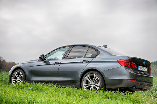 Breuberg, Germany- April 21, 2013: 2013 BMW 3 Series (320d) parked outside in a suburban grass field. The BMW 3-Series is a compact executive car produced by the German car manufacturer BMW.  BMW (Bayerische Motorenwerke AG) is a german automobile manufacturing company based in Munich, Bavaria. This is the 2013 Sport Line edition.
