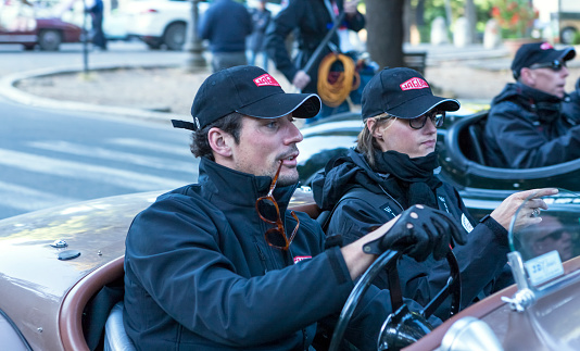 Rome, Italy - May 18, 2013: british model David Gandy and fashion icon Yasmin Le Bon on a Jaguar XK-120-OTS (1950) racing car on the third, and last, day of Mille Miglia race, leaving Rome in the early morning to reach Brescia for the race's conclusion. Mille Miglia nowadays is a competitive re-enactment of the world-famous homonymous rally who took place between 1927 and 1957 along Italy's streets, cities and  towns. Its strict rules allow only cars whose model participated at least once to the actual rally, and 2013 edition counted more than 350 vintage cars with noticeable drivers and co-drivers such as former F1 pilots, models, actors, fashion icons, car-company founders' descendants and many others along with common passionated people. Mille Miglia has been called 'the most beautiful race in the world'.