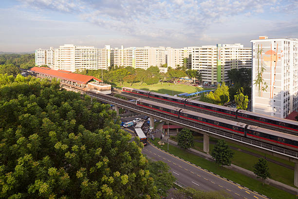 Singapore, Singapore - May 17, 2013: MRT trains (Mass Rapid Transit) reaching and leaving Khatib MRT Station, commuters in vehicles at a busy traffic junction, the pedestrian crossing the roads in the morning.