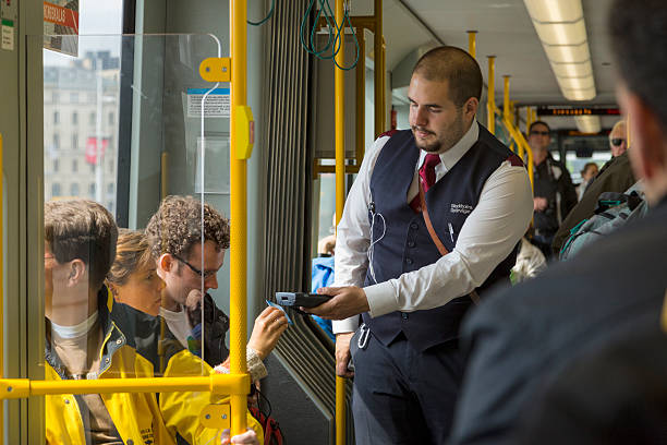 Ticket collector on Stockholm tram. Stockholm, Sweden - May 24, 2013: Ticket collector on Stockholm tram. He is eradinga card with his card reader. Passengers are sitting and standing in the tram. A Stockholm building can be seen through the window. transport conductor stock pictures, royalty-free photos & images