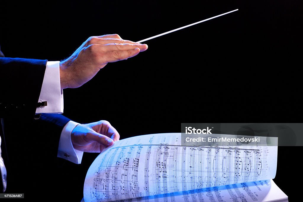 Music conductor using stick and turning the sheet music page Conductor's hands with a baton and music score Musical Conductor Stock Photo