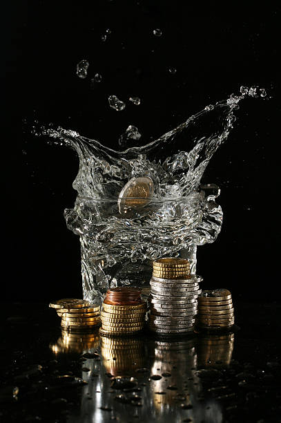 istock Coins falling into a glass of water with splash 471537139