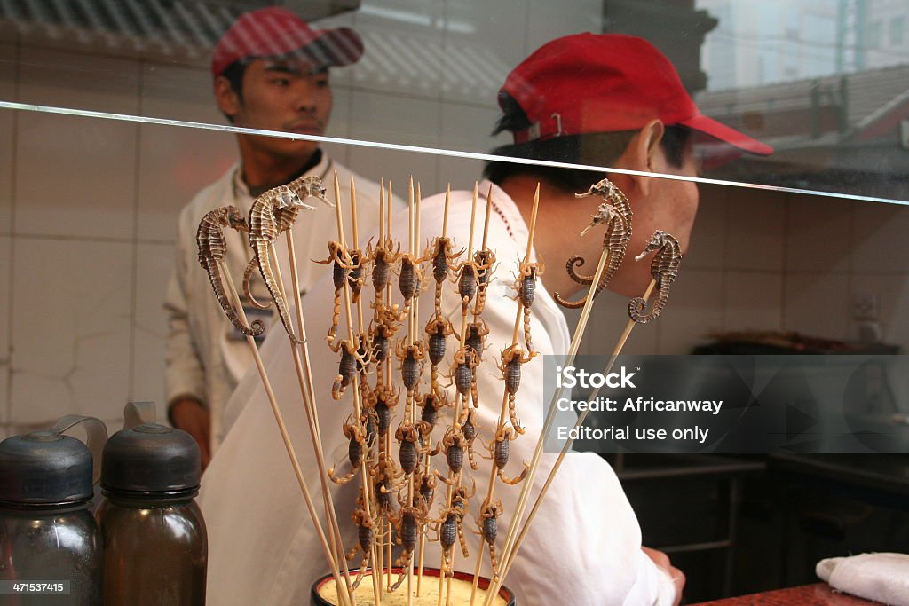 Sea Horses and Scorpions at a Chinese Takeaway, China Shanghai, China - October 26, 2005: Takeaway selling Sea horses and Scorpions on a stick. The two cooks are very busy. Animal Stock Photo