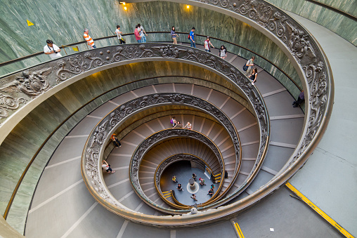 Rome, Italy - April 19, 2013: The famous spiral staircase that leads to the exit of the vatican museum inside the vatican city. Tourists are walking down.