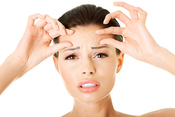istock beautiful woman checking her wrinkles on forehead. 471538485