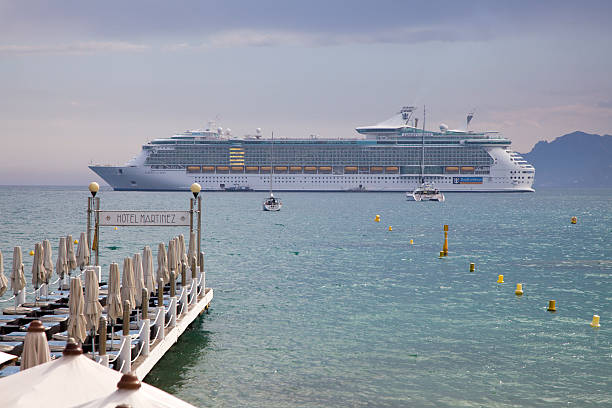 Cannes, France - May 6, 2013: A huge cruise ship anchors in Cannes bay in front of the beach and jetty of Hotel Martinez a week ahead of the Film Festival. 