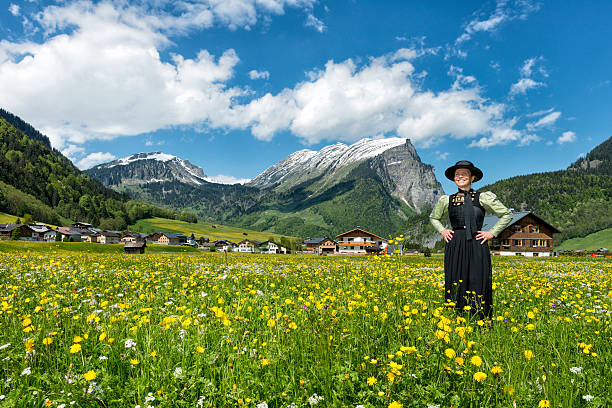 glückliche ältere frau tragen dirndl stehen in blüte wiese - österreich tracht stock-fotos und bilder