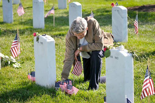 Arlington, Va. USA - May 27, 2013: A woman visits a veteran's grave stone at Arlington National Cemetery on Memorial day. 