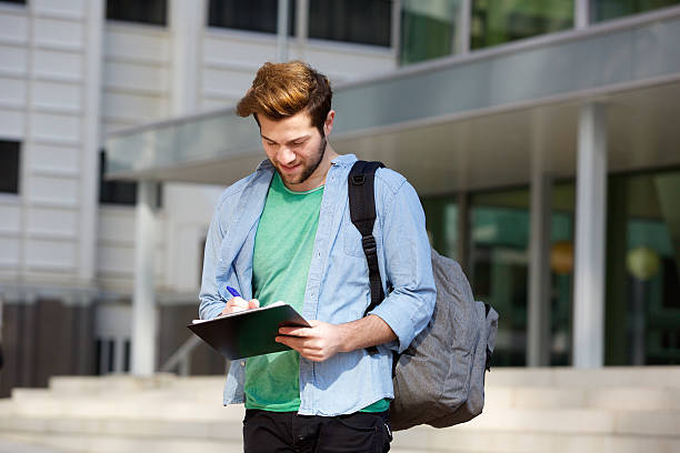 istock Male college student standing outside with notepad and bag 471545076