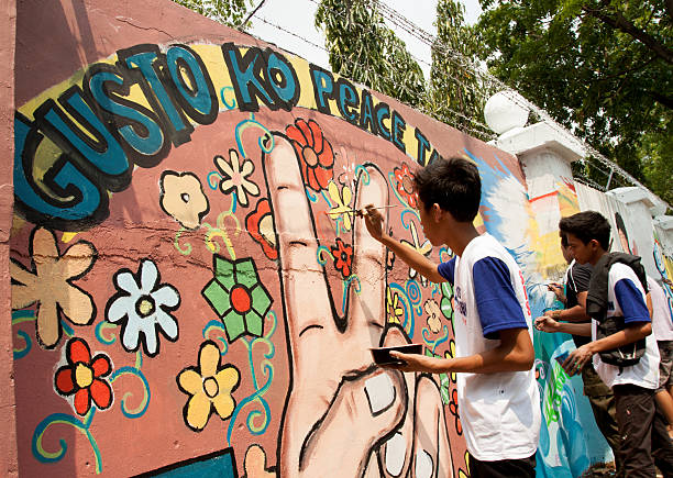 Painting  sign of peace in the wall Quezon City, Philippines - June 1, 2013: An attempt to make 3,770 meters of peace mural along the major national highway in Manila, which will be considered the longest peace mural in the world surpassing the Guinness record "Chile Wall of Peace" which is only 1,000 meters. The project " A journey of peace" was started May 26th, 2013 with several peace advocates groups including the Armed Forces of the Philippines. guinnes stock pictures, royalty-free photos & images