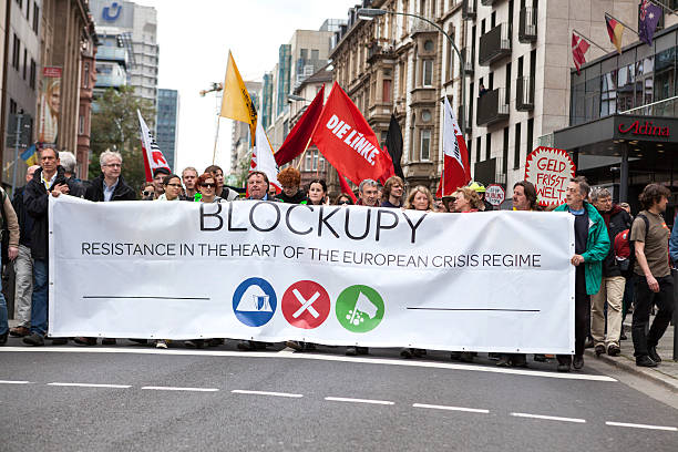 Protestors at Blockupy 2013 demonstration, Frankfurt Frankfurt, Germany - June 1, 2013: Protestors at Blockupy 2013 demonstration in the city center of Frankfurt holding up banners. Blockupy is a left-wing political network of several organizations. The name derives from its plan for a "blockade" and the Occupy movement. protestors at blockupy 2013 demonstration frankfurt stock pictures, royalty-free photos & images