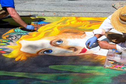 Lake Worth, United States - February 24, 2013:Two artists compete in the yearly Lake Worth street art festival. They are using chalk to make the detailed temporary drawings.