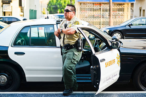 LA Sheriff coming out of the car on Hollywood Boulevard Hollywood, USA - May 31, 2013: Sheriff Car on Hollywood Boulevard, man in uniform leaning on car watching crowds of people walking along famous Hollywood Walk of fame. lypsela2013 stock pictures, royalty-free photos & images