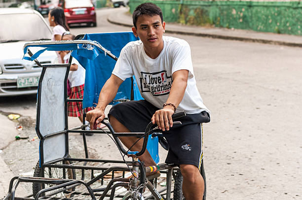 Tricycle Driver Cebu, Philippines - October 17, 2012: Young man waiting on his bicycle for passenger or cargo fares on the streets of Cebu, Philippines, Asia. philippines tricycle stock pictures, royalty-free photos & images