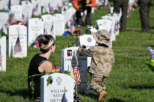 Arlington, Va. USA - May 27, 2013: A young woman and her son visit a grave at Arlington National Cemetery on Memorial Day.