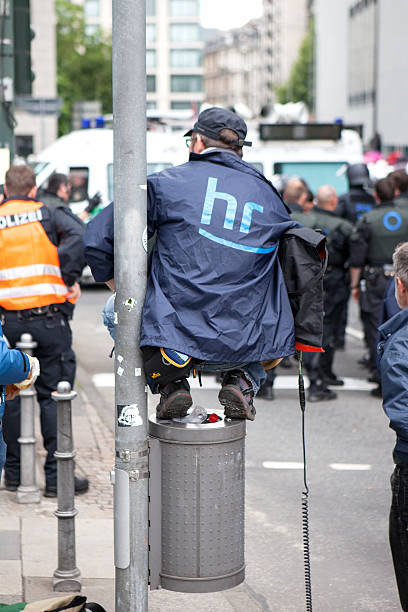 Blockupy demonstration 2013, Frankfurt Frankfurt, Germany - June 1, 2013: A member of German broadcasting station Hessischer Rundfunk tries to get a closer look at the scene by using a public dustbin during Blockupy demonstration 2013 in the city center of Frankfurt. protestors at blockupy 2013 demonstration frankfurt stock pictures, royalty-free photos & images