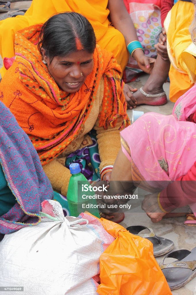 Colors of love - Kumbh Mela 2013 Allahabad, India – Feb 24, 2013: An Indian women massaging her mothers leg in open ground after walking for ten miles on foot, shot taken during Kumbh event in Allahabad, India. 2013 Stock Photo