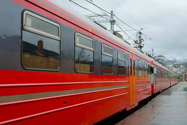 red train stopping at a station