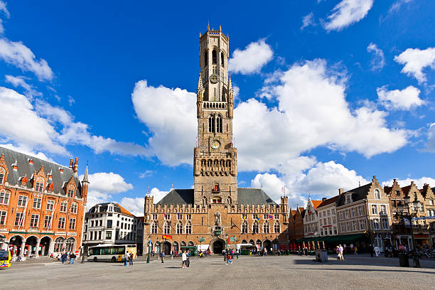 Bruges, Belgium - June 22, 2012: The Belfry (Belltower) in the Market Square (Markt).  It is a medieval bell tower in historic city center. Bruges has most of its medieval architecture well preserved and has been designated a UNESCO World Heritage Site. Tourists are walking around.