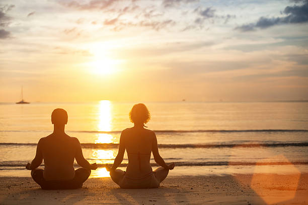 istock Young yoga couple meditating on the coast. 471551184