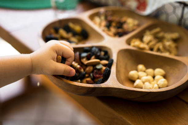 istock A toddler picking almonds from a wooden bowl of mixed nuts 471552570