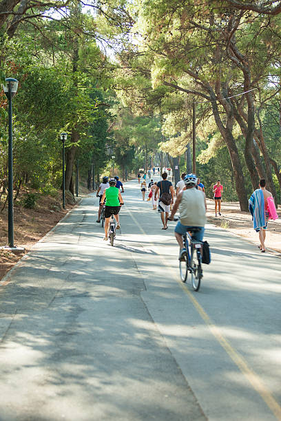 Mature women ride bicycles on promenade at sunset, Finale Ligure, Liguria