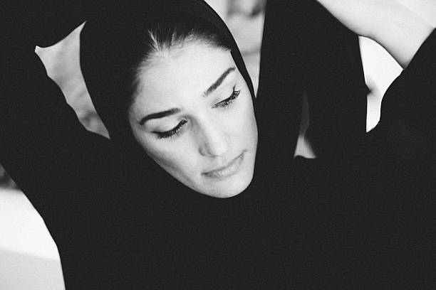 Two beautiful middle eastern women under single black religious veil. Focus on left girls right eye.