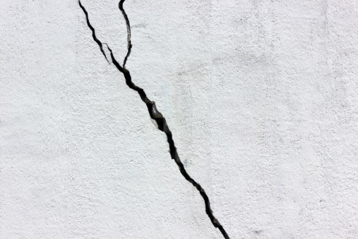 A clear diagonal black fissure on white wall